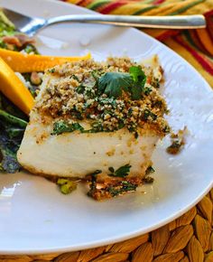 a white plate topped with fish covered in toppings next to broccoli and lemon wedges