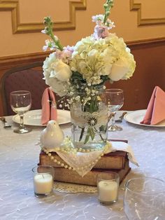 the table is set with white flowers and place settings for two people to sit at