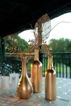 three gold vases sitting on top of a table