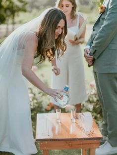 a bride and groom are getting ready to pour water into their glasses at the ceremony