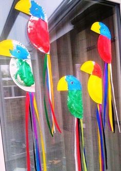 three paper plates with birds on them hanging from the side of a window sill