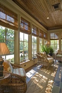 a sun room with wicker furniture and lots of windows on both sides of the room