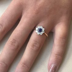 a woman's hand with a diamond and sapphire ring on her left hand,