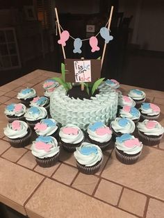 cupcakes are arranged on a table in front of a cake that has been decorated with blue and pink frosting