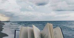 an open book sitting on top of a boat near the ocean