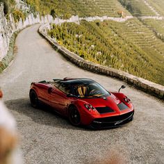 a red sports car parked on the side of a road next to a vineyard field