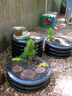 several tires are stacked on top of each other in the yard, with plants growing out of them