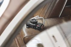 a camera sitting on top of a brown leather seat next to a white door handle