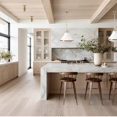 a kitchen with white marble counter tops and wooden chairs in front of a large window