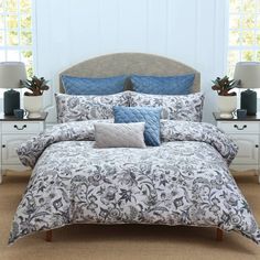 a bed with blue and white comforters in a bedroom next to two nightstands