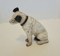 a ceramic dog figurine sitting on top of a white table next to a wall