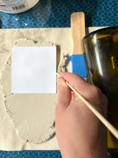 someone is using a wooden stick to paint the edges of a piece of white paper