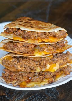 three quesadillas stacked on top of each other on a white plate with cheese