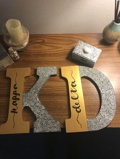 a wooden table topped with two metal letters and a candle on top of the table