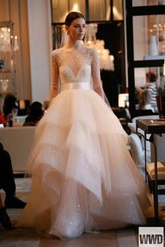 a woman in a wedding dress is walking down the runway