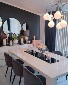 a dining room table and chairs with candles on it in front of three round mirrors