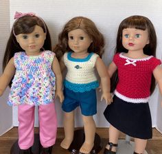 three dolls standing next to each other in front of a white wall and wooden floor