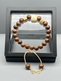 Experience the elegance of our Golden Sandalwood Bracelet, a luxurious piece crafted with precision and care. Each bead measures approximately 0.39 inches in width and thickness, providing a substantial yet comfortable feel on your wrist. The adjustable length ensures a perfect fit for any wrist size, making this bracelet a versatile accessory suitable for everyone. Golden Sandalwood is prized for its beautiful golden hues and subtle, natural fragrance. Known for its calming and grounding properties, this bracelet is more than just an accessory; it's a piece of wearable tranquility. Ideal for meditation and mindfulness practices, it helps to promote a sense of inner peace and balance. The classic design of the Golden Sandalwood Bracelet adds a touch of sophistication to any outfit, whether Wood Beads Jewelry, Sandalwood Bracelet, Mindfulness Practices, Peace And Balance, Elegant Bohemian, Spiritual Wellness, Wellness Gifts, Natural Fragrances, Natural Beads