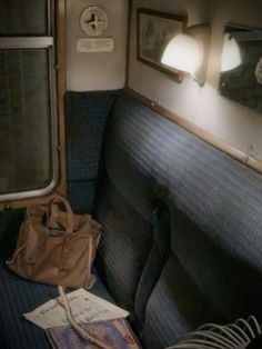 an empty seat on a train with a purse and mirror in the back ground next to it