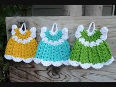 three crocheted dresses hanging on a clothesline in front of a wooden wall