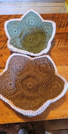 two crocheted bowls sitting on top of a wooden table