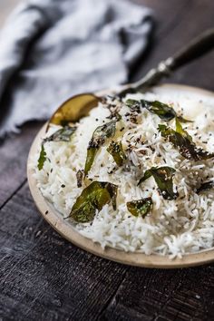 white rice with green peppers and spices in a bowl on a wooden table next to a napkin