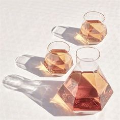 three glass vases filled with liquid on top of a white tablecloth covered floor