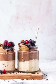 two jars filled with food sitting on top of a wooden cutting board next to each other