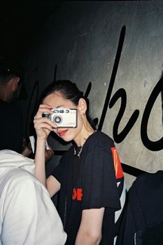 a woman holding up a camera to take a photo with another person in the background