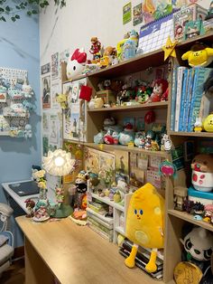 a room filled with lots of stuffed animals and toys on shelves next to a desk