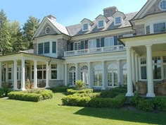 a large white house with lots of windows and columns on it's front lawn