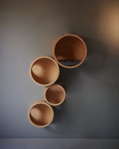 three wooden bowls are hanging on the wall in front of a gray wall and floor