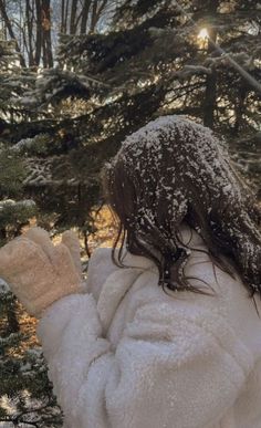 a person in a white coat and mittens standing outside with snow on their hands