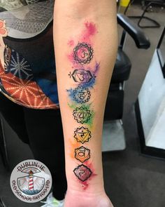 a person with a tattoo on their arm that has seven chakras painted on it