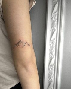 a woman's arm with a small mountain tattoo on the left side of her arm