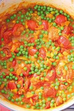 a pot filled with peas and tomatoes on top of a stove