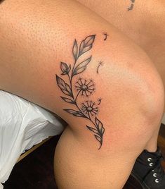 a woman's thigh with a flower tattoo on her left leg and a dandelion in the middle