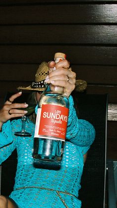 a woman in a blue dress is drinking from a bottle