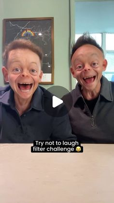 two young boys sitting at a table with their mouths open and one boy is laughing