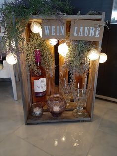 a wine bottle and two glasses in a wooden crate with lights on the sides that says win laube