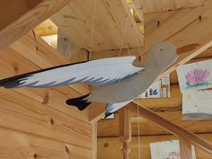 a bird hanging from the side of a wooden building with paintings on it's walls