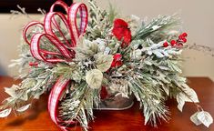 a red bird sitting on top of a wooden table covered in greenery and candy canes