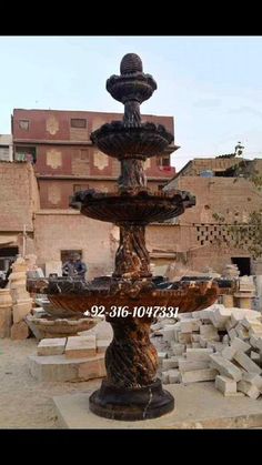 an outdoor fountain in the middle of a courtyard with brick walls and buildings behind it