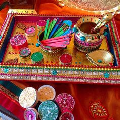 the tray is filled with different colored items and beads on it, as well as other decorative objects