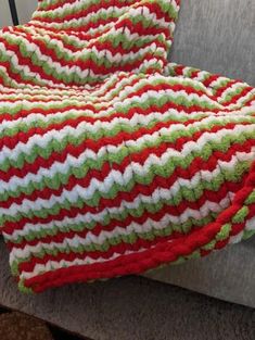 a crocheted blanket sitting on top of a gray couch next to a pillow