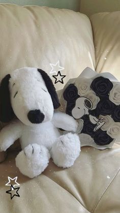 a white stuffed dog sitting on top of a couch next to a star shaped pillow