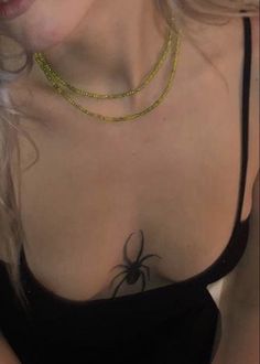 a close up of a woman wearing a black top with a spider tattoo on her chest