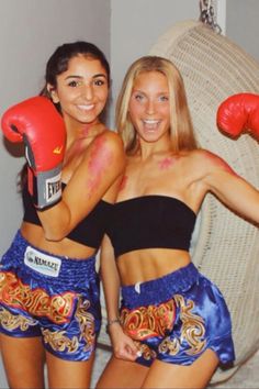 two women wearing boxing gloves pose for a photo