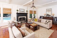 a living room filled with furniture and a fire place under a chandelier on top of a hard wood floor