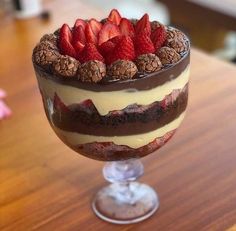 a dessert with chocolate, strawberries and cream in a glass on a wooden table